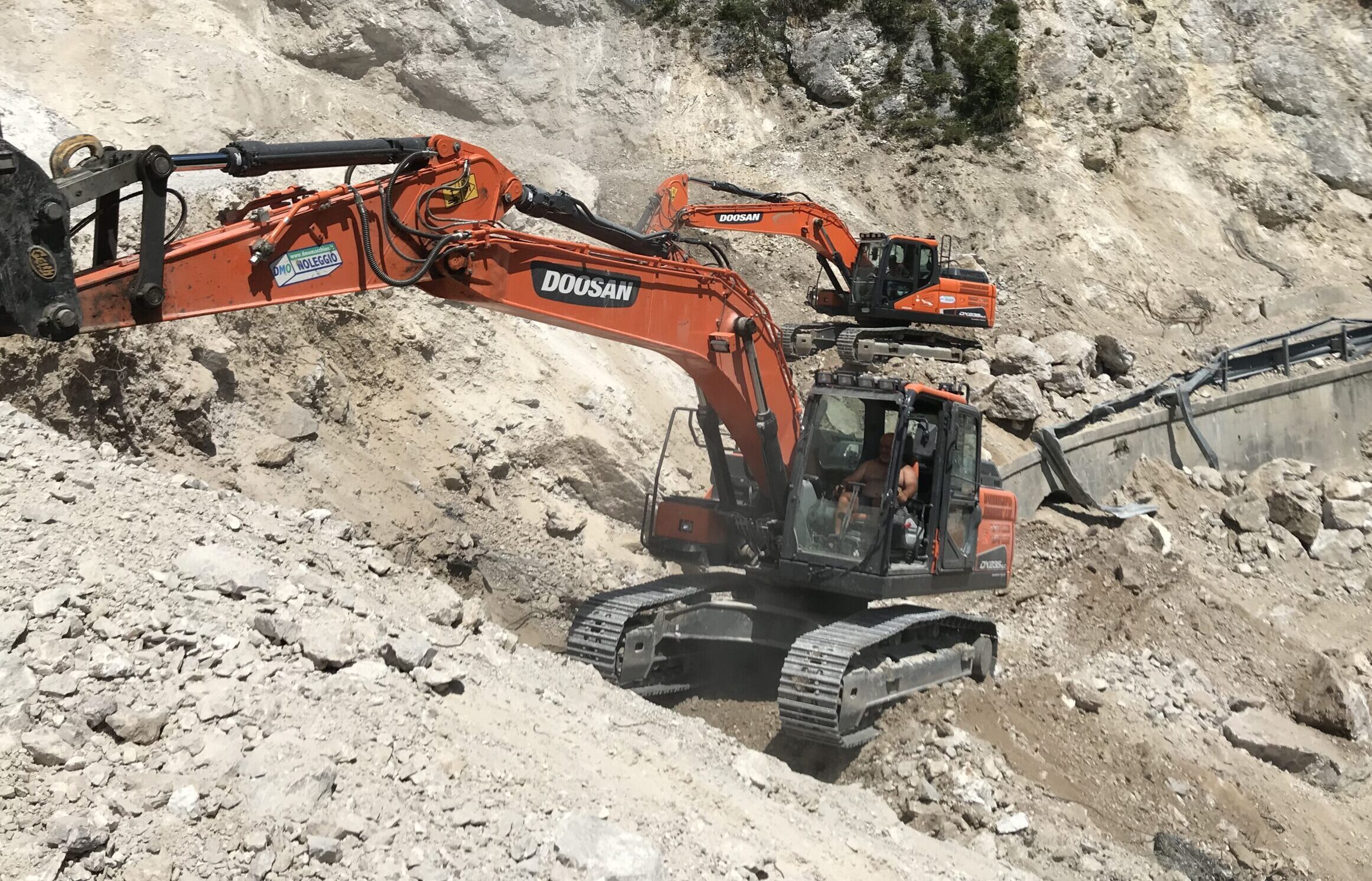 scavatore meccanico in azione per rimozione della frana sulla strada