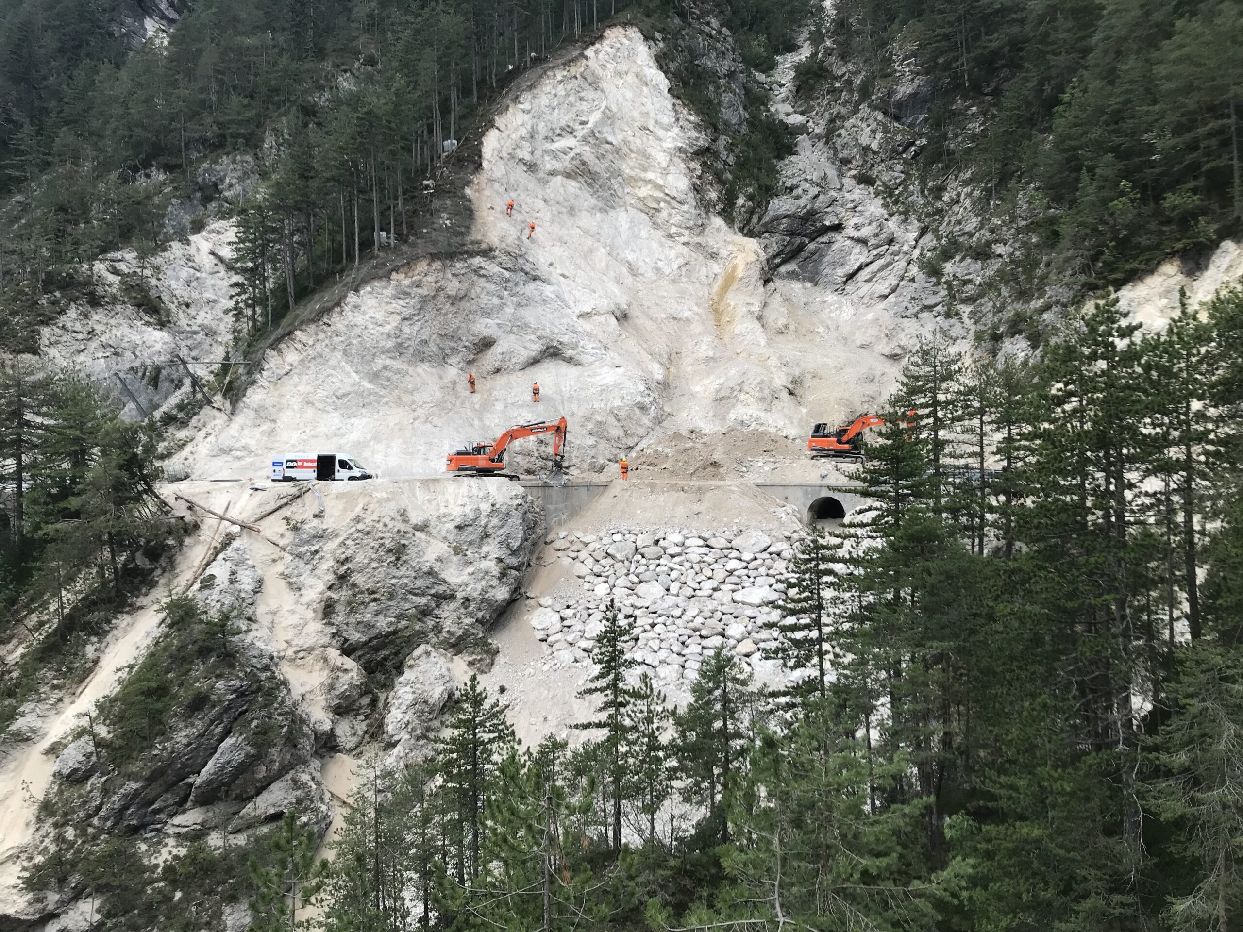 Operai appesi su corda che disgaggiano una parete franosa a bordo strada
