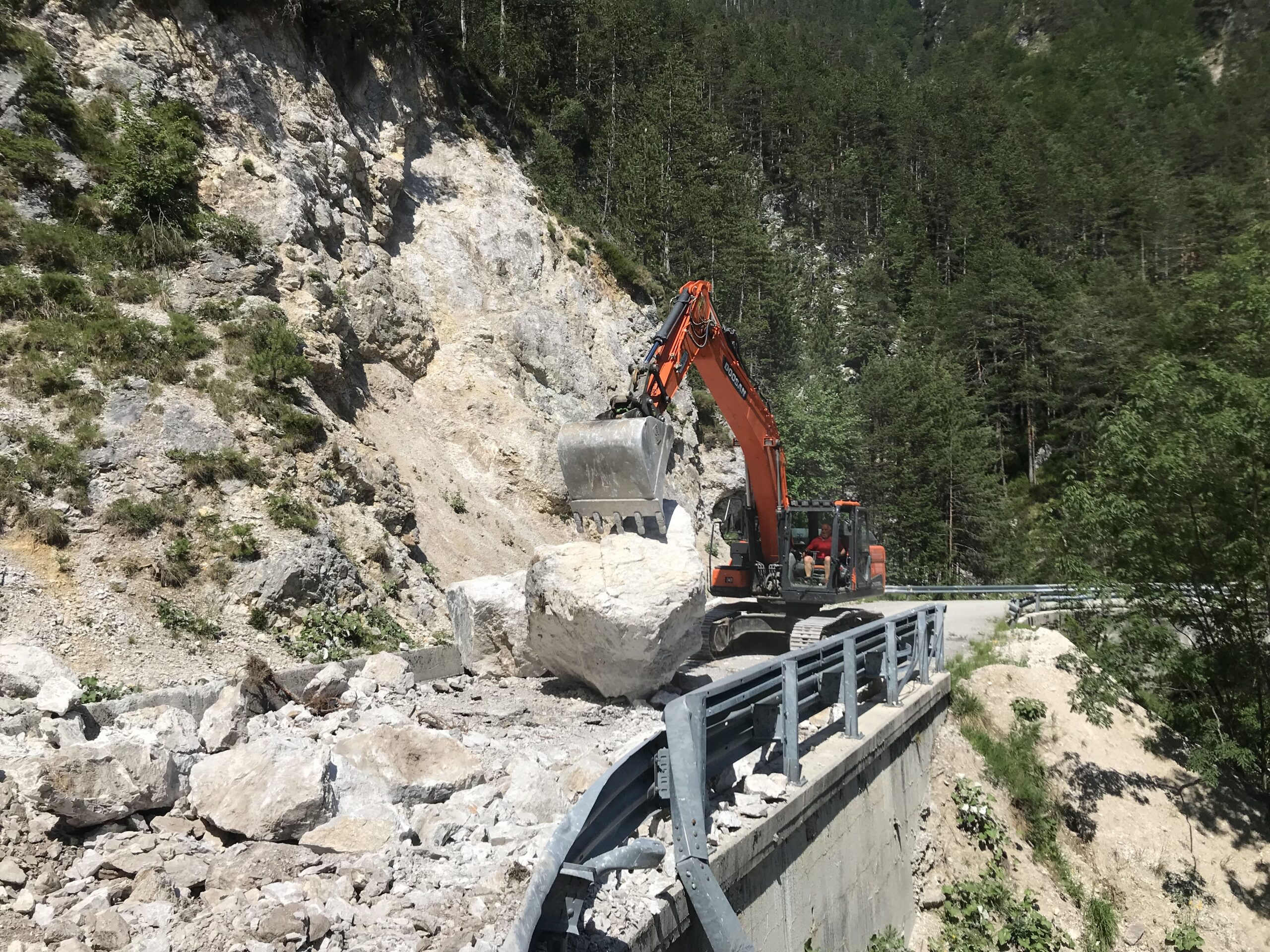 scavatore meccanico in azione per rimozione della frana sulla strada