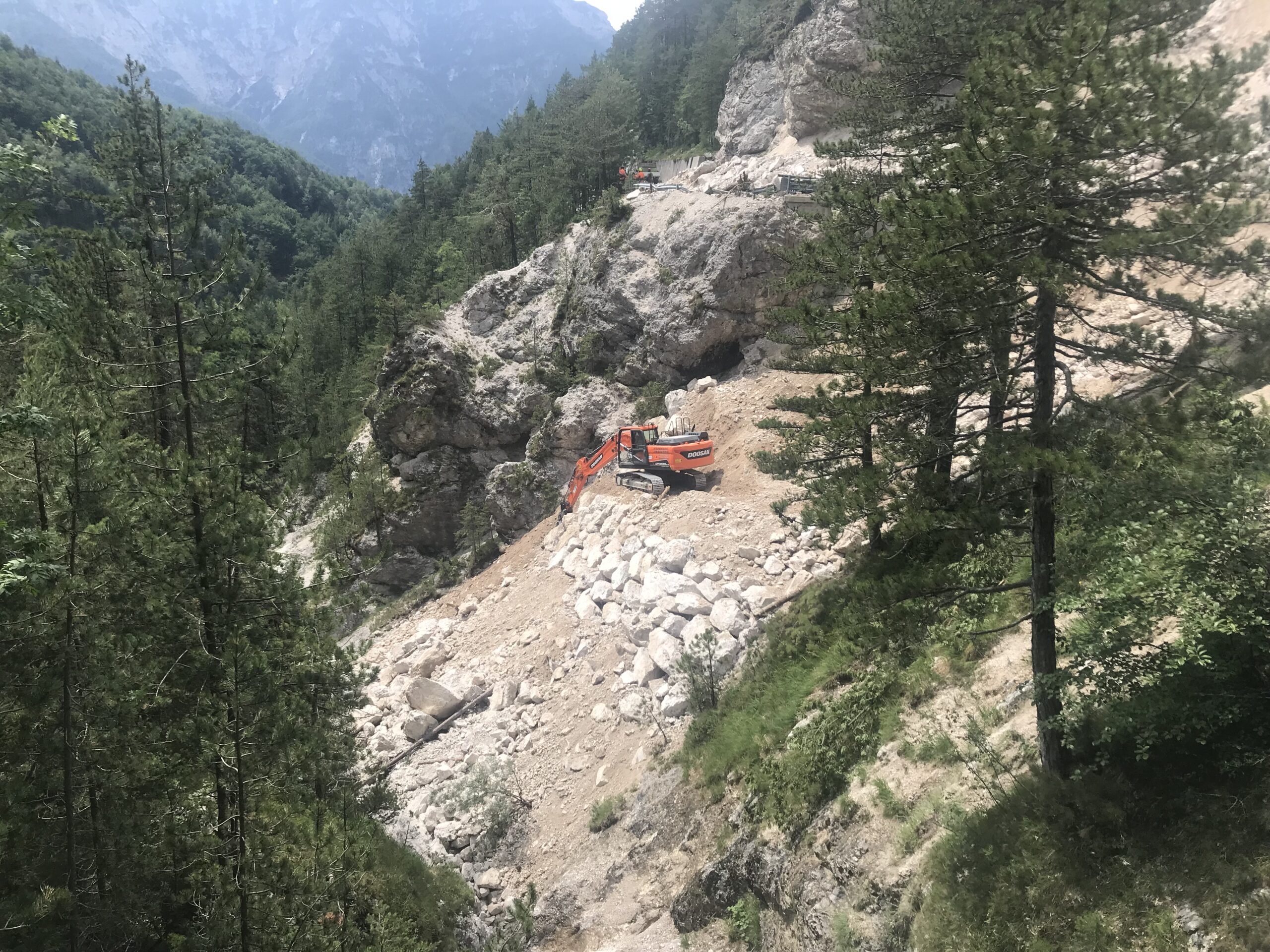 Mezzo meccanico in azione per posizionamento blocchi di argine frana stradale