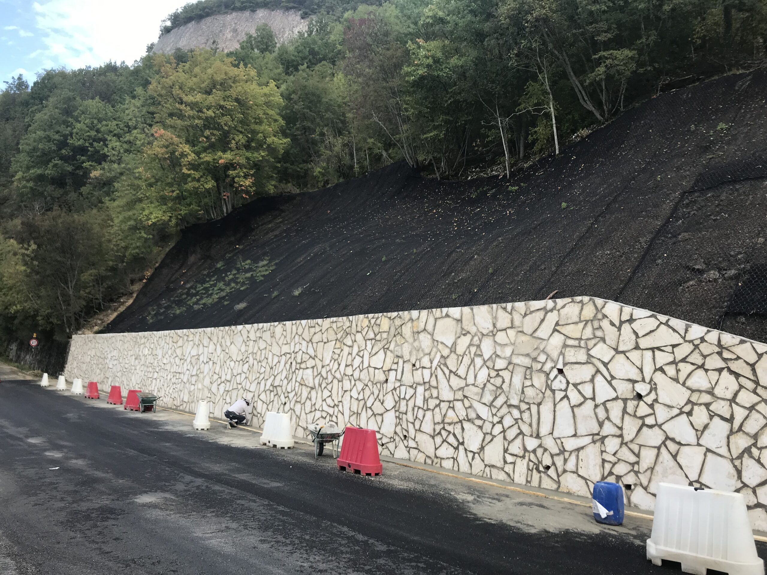 Costruzione di un muro in pietra a bordo strada dopo rimozione frana